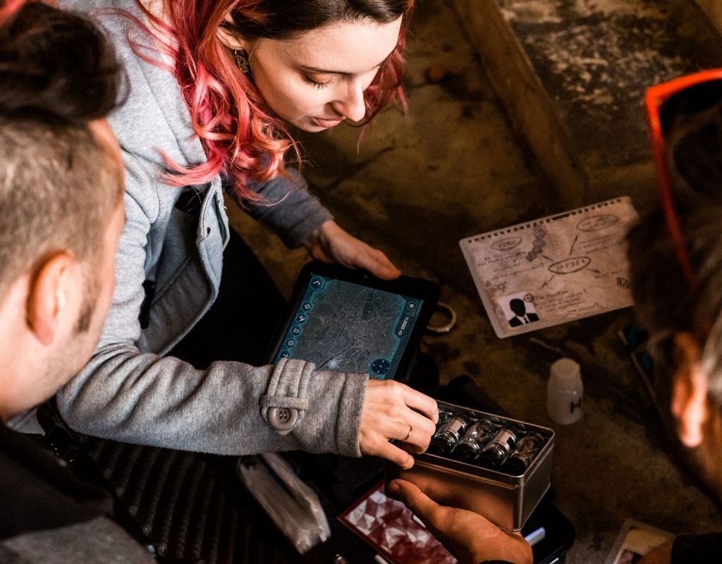 3 joueurs manipulent des objets fioles médicales une tablette tactile