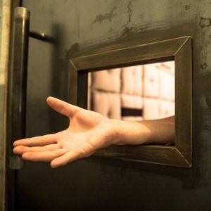 un prisonnier passe une main à travers le passe-plat de sa cellule